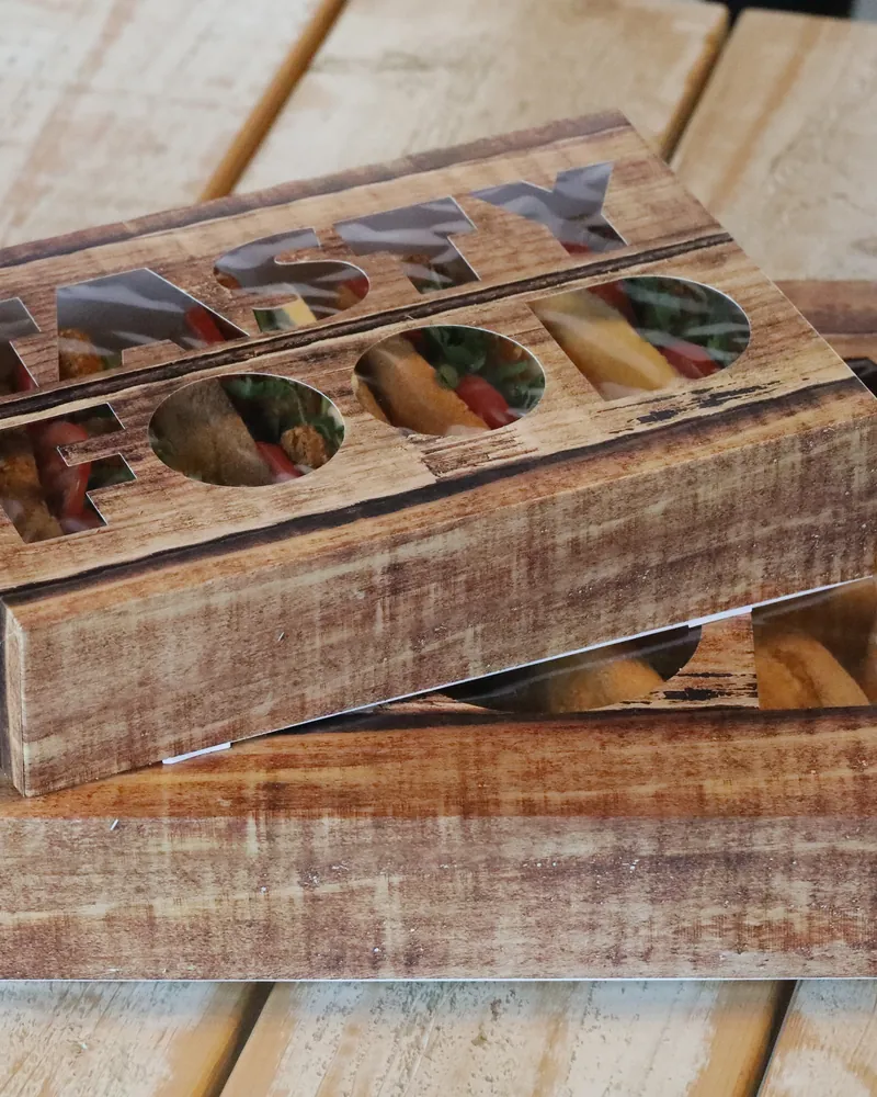 A laser-cut wooden display box holding falafel sandwiches