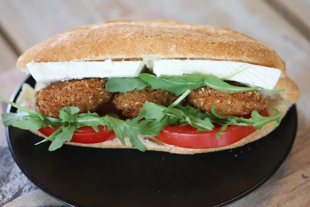A falafel sub on sesame bread with rocket, tomato and garlic sauce