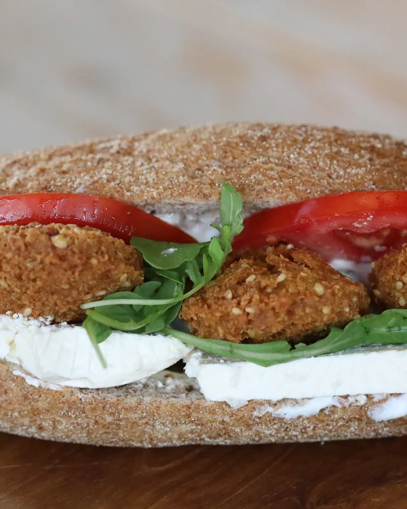 A falafel sandwich photographed close on a dark board