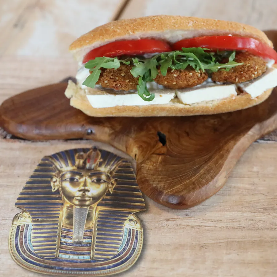 A falafel roll with tomato and dressing on wood