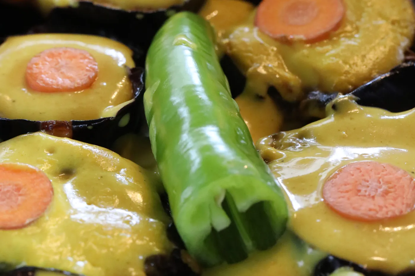 A tray of aubergine rounds glazed in a golden sauce with carrot and chilli