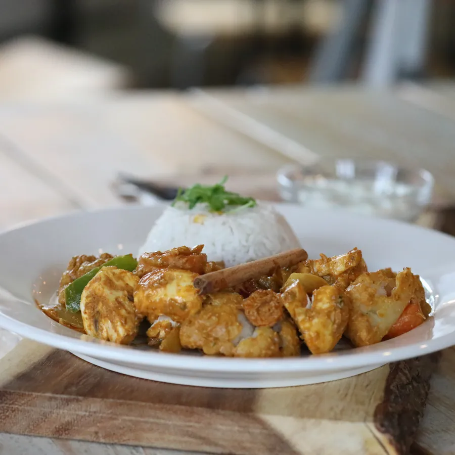 A plate of spiced chicken with rice and dip